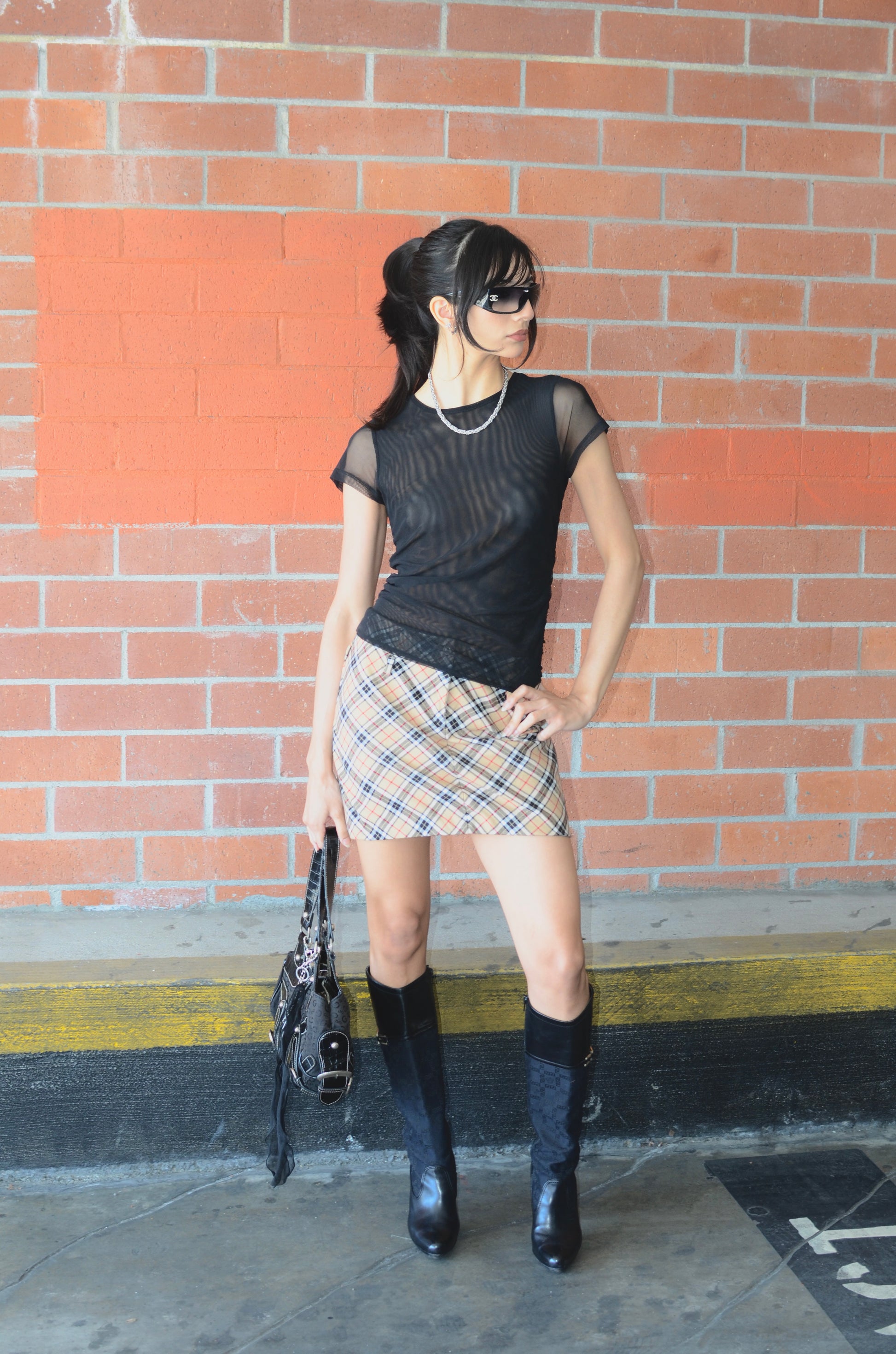 Model wearing black tee, black versace boots, black guess bag, chanel sunglasses, and a vintage Dolce & Gabbana plaid mini skirt displayed on a mannequin, with a side zipper, in a great condition.