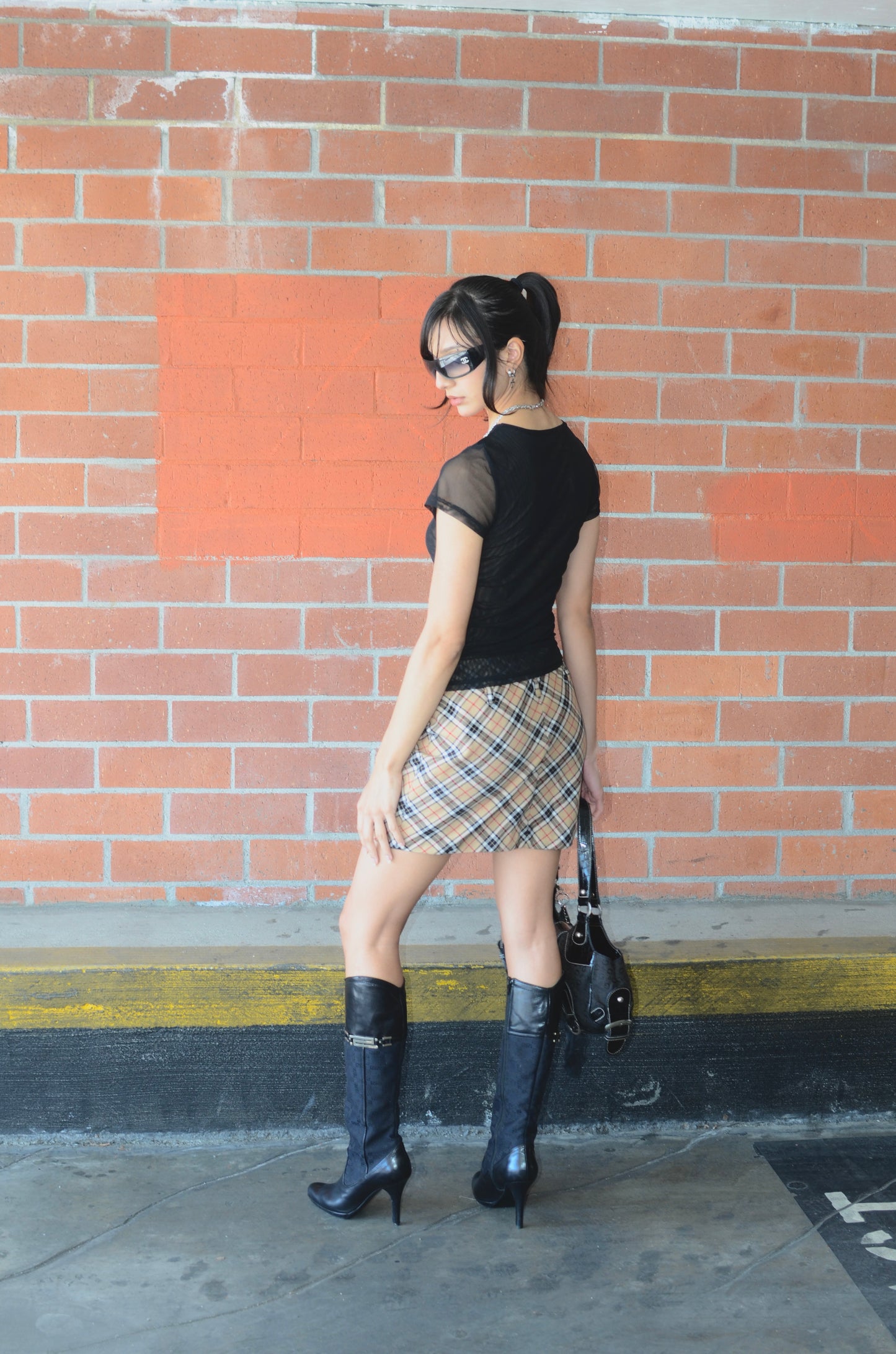 Model wearing black tee, black versace boots, black guess bag, chanel sunglasses, and a vintage Dolce & Gabbana plaid mini skirt displayed on a mannequin, with a side zipper, in a great condition.