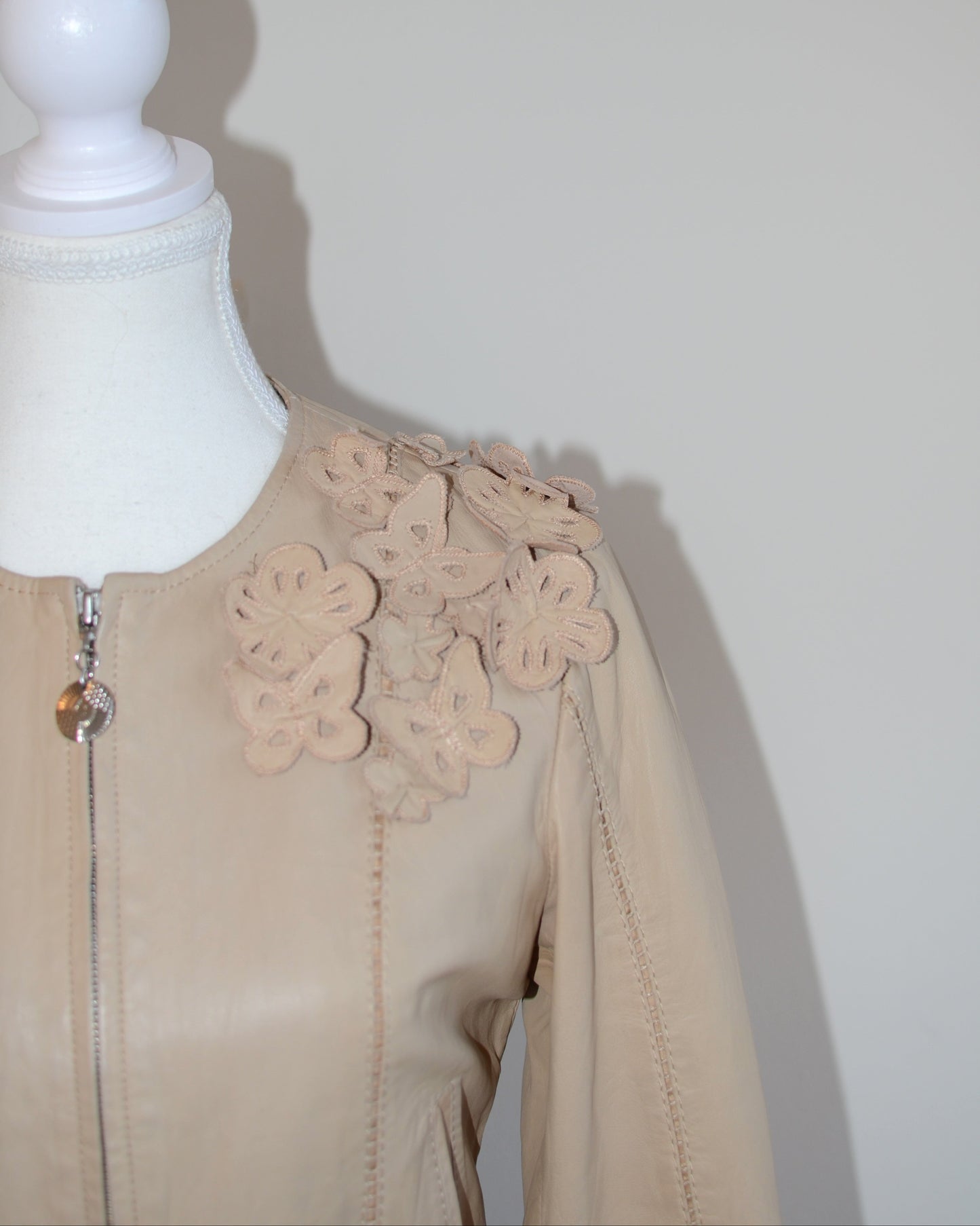 Roberto Cavalli Beige leather jacket with floral embellishments on a mannequin against a white background